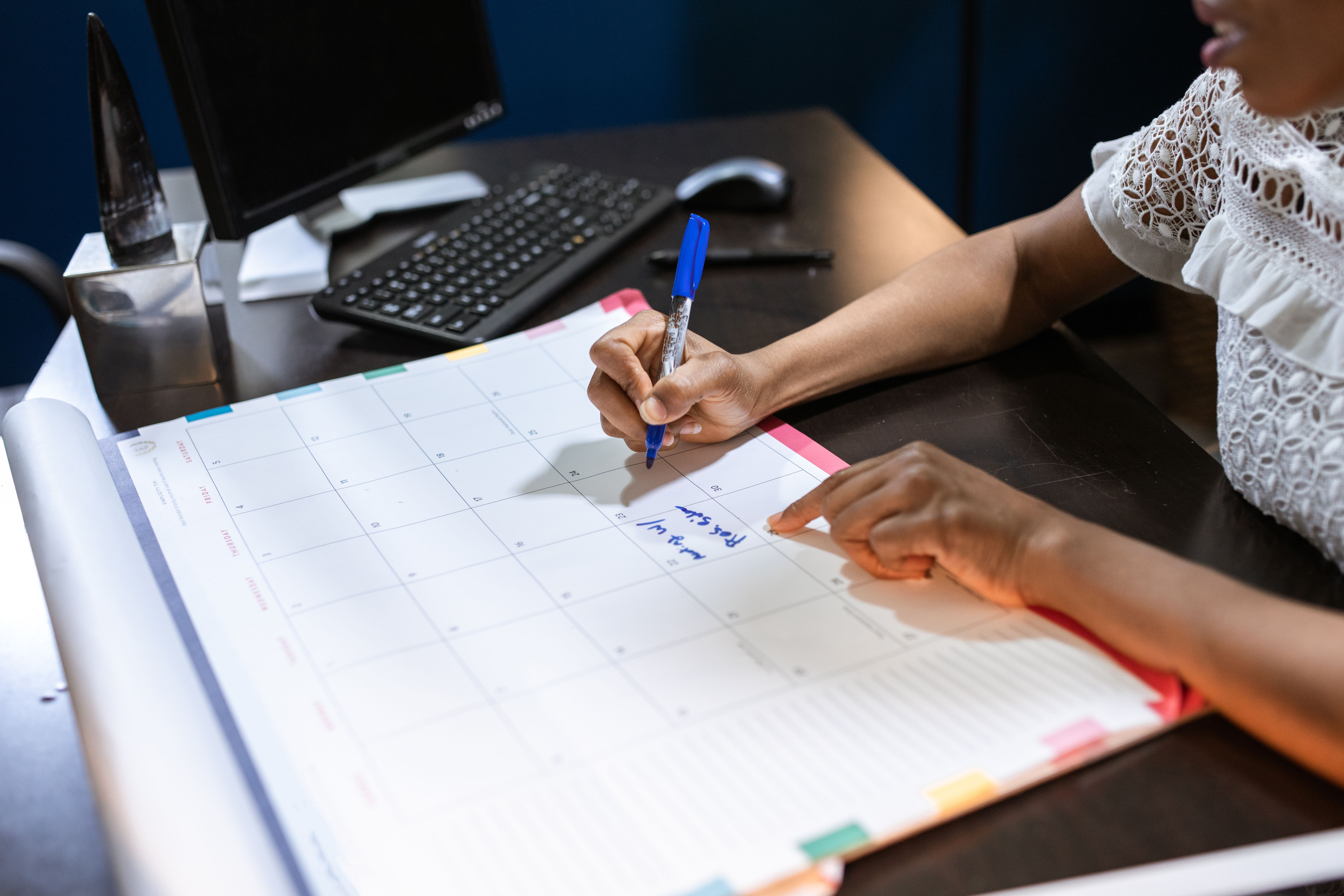 Person writing notes in a desk calendar for planning healthcare updates